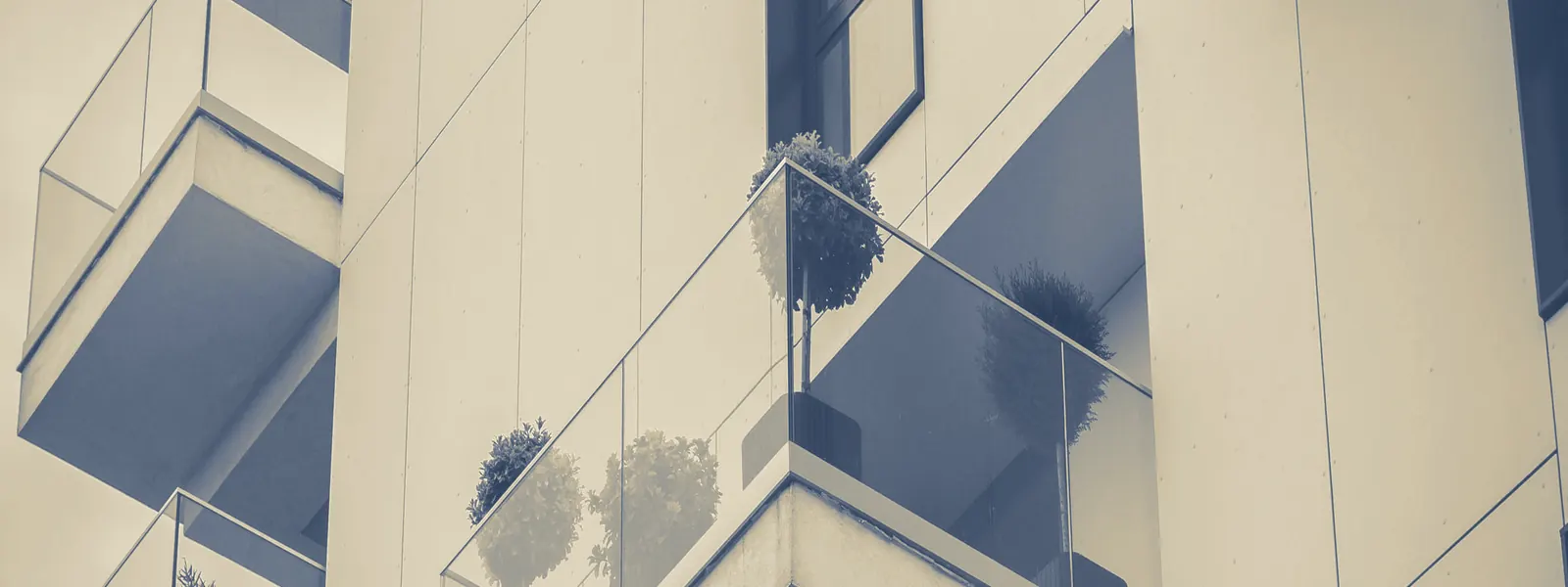 Fachada de un edificio residencial con balcones acristalados, en duotono azul